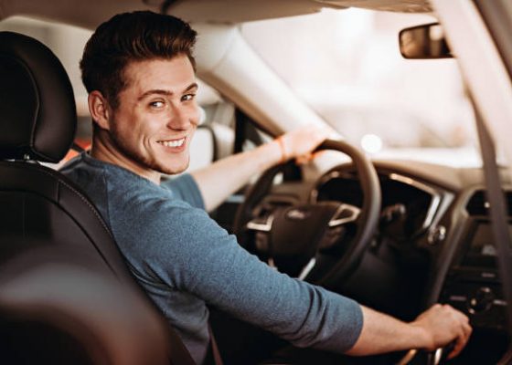 Happy young driver behind the wheel of a car. Buying a car and driving concept Happy young driver behind the wheel of a car. Buying a car and driving concept